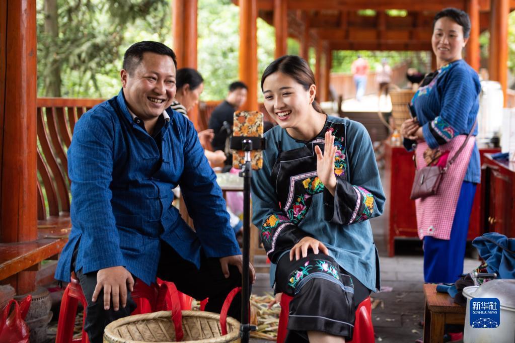 在湖南湘西十八洞村，十八洞村扶贫队长麻辉煌（左）与返乡大学生施林娇（中）一起直播推销土特产（2020年5月15日摄）。新华社记者 陈思汗 摄